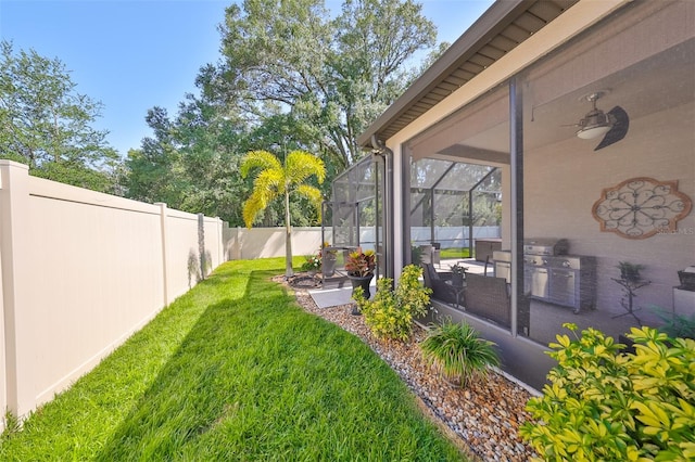 view of yard with ceiling fan, a lanai, and a patio