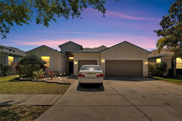 ranch-style home featuring a garage and a yard