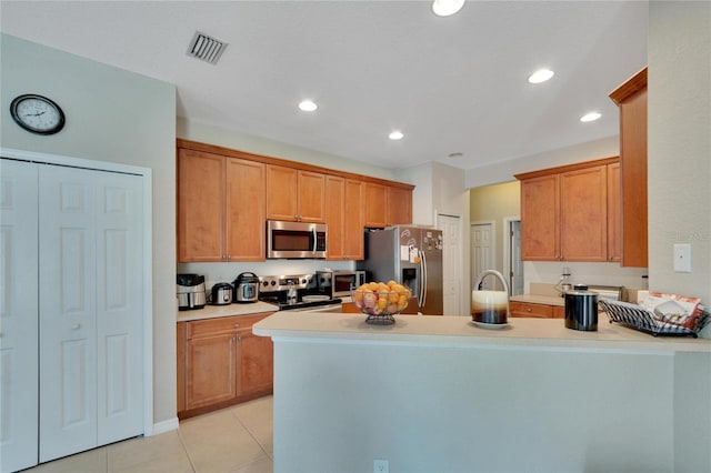 kitchen featuring light tile patterned floors, kitchen peninsula, and stainless steel appliances