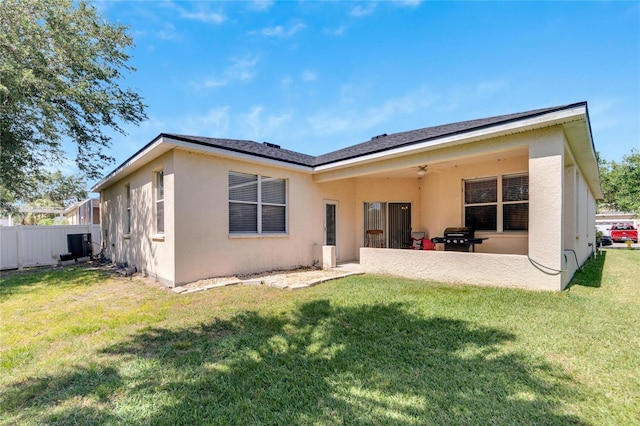 back of house featuring a lawn, ceiling fan, and a patio area