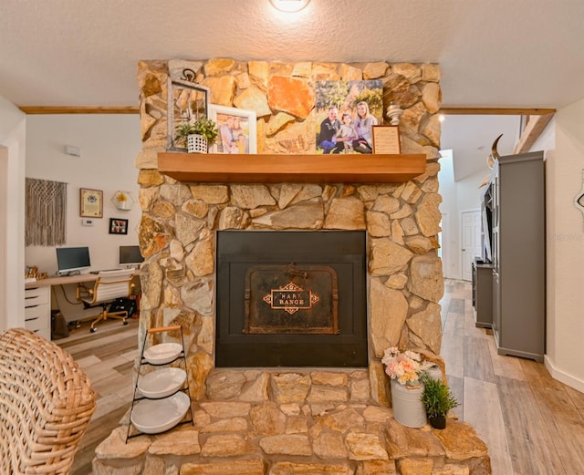 room details featuring light hardwood / wood-style floors, a stone fireplace, and a textured ceiling