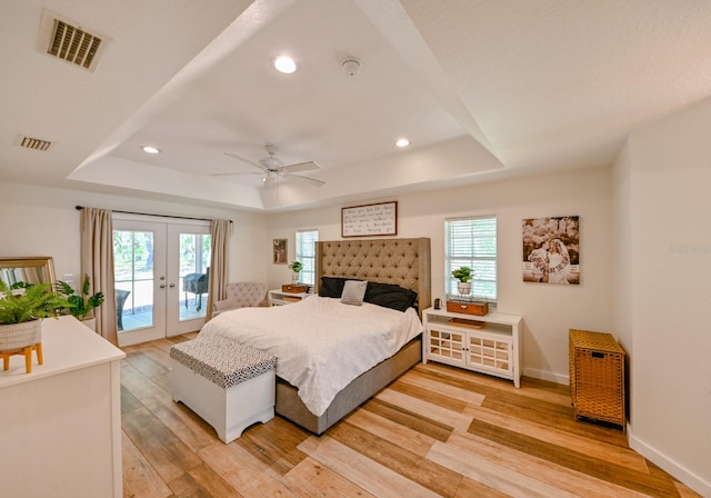 bedroom with light hardwood / wood-style flooring, access to exterior, and a raised ceiling