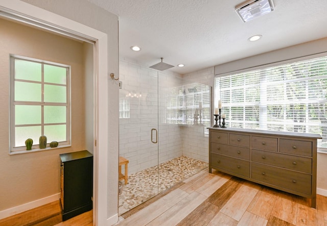 bathroom featuring a healthy amount of sunlight, wood-type flooring, a textured ceiling, and a shower with door