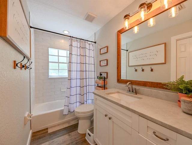 full bathroom with hardwood / wood-style floors, large vanity, shower / bathtub combination with curtain, and toilet