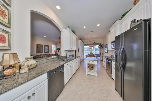 kitchen with decorative light fixtures, white cabinets, black appliances, light tile floors, and dark stone countertops