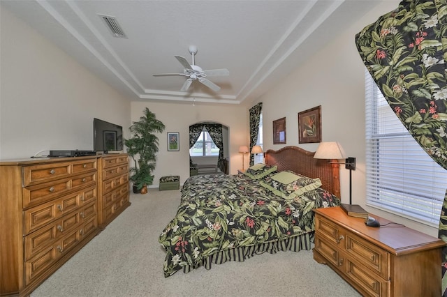 carpeted bedroom featuring a raised ceiling and ceiling fan