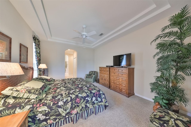 carpeted bedroom with ceiling fan, a tray ceiling, and ensuite bathroom