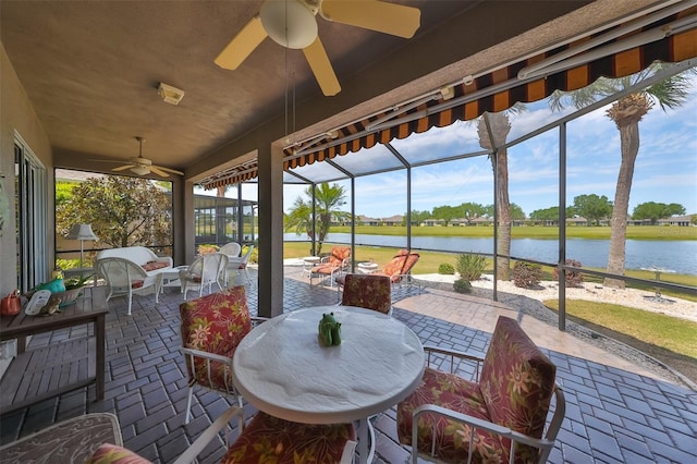 sunroom / solarium featuring ceiling fan and a water view