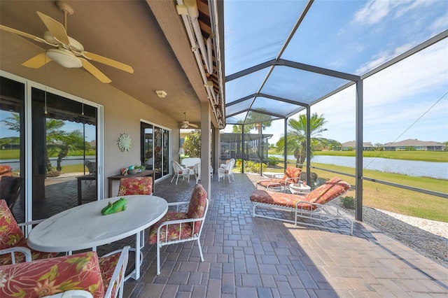 sunroom featuring ceiling fan and a water view