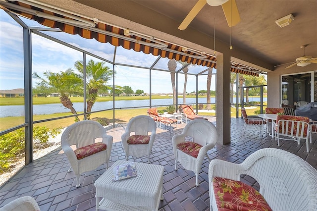 sunroom with ceiling fan and a water view