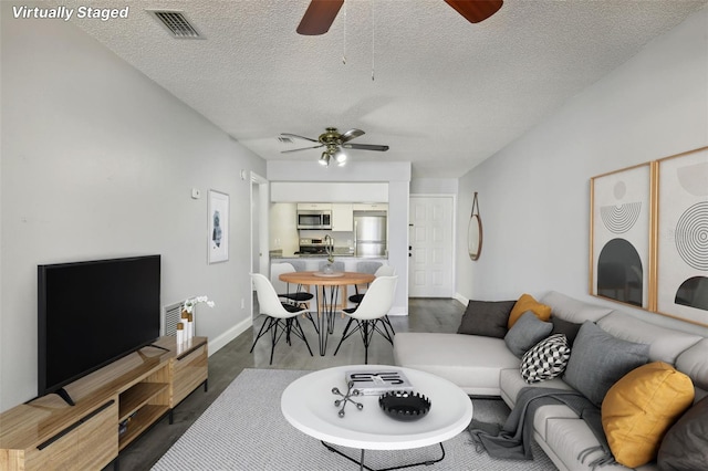 living room featuring ceiling fan, a textured ceiling, and wood-type flooring