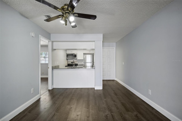 unfurnished living room featuring sink, dark hardwood / wood-style flooring, ceiling fan, and a textured ceiling