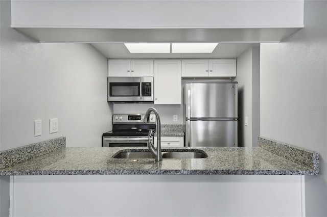 kitchen featuring stone countertops, appliances with stainless steel finishes, sink, and white cabinets