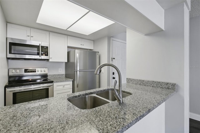 kitchen featuring appliances with stainless steel finishes, white cabinetry, sink, and light stone counters