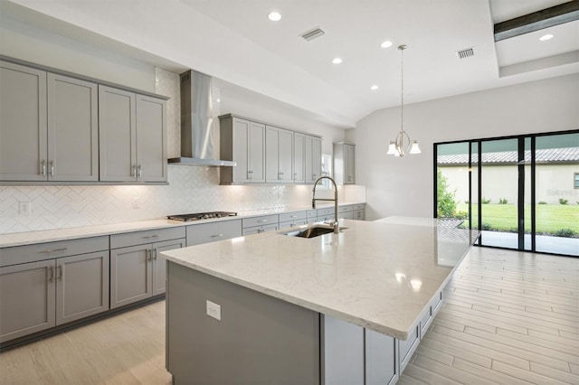 kitchen with gray cabinetry, visible vents, a sink, and wall chimney exhaust hood