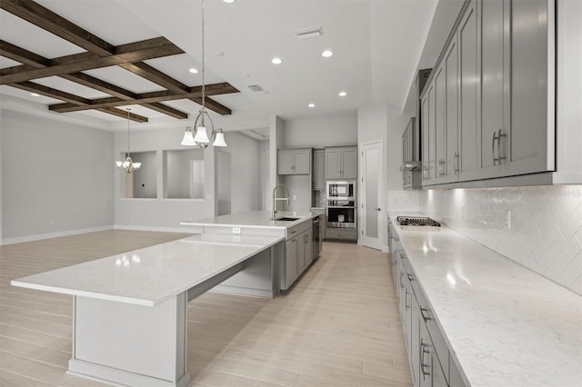 kitchen with tasteful backsplash, coffered ceiling, appliances with stainless steel finishes, gray cabinets, and a sink