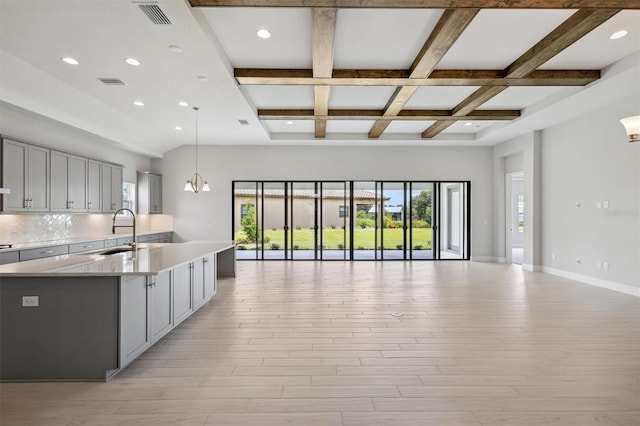 kitchen with open floor plan, gray cabinets, a sink, and visible vents