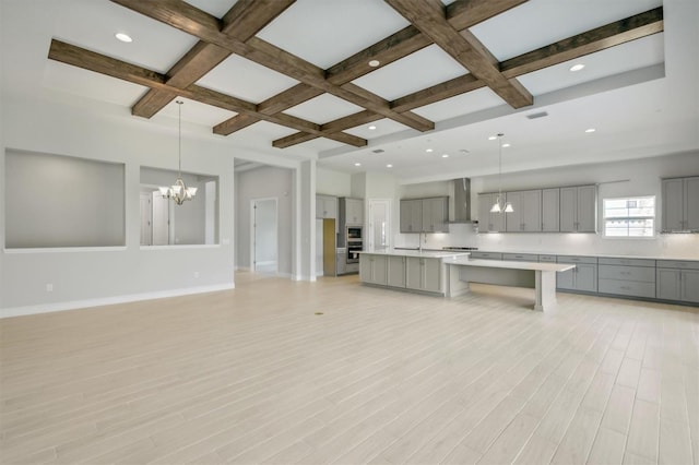 kitchen featuring pendant lighting, light hardwood / wood-style floors, gray cabinetry, a center island, and wall chimney range hood