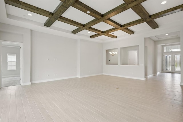 empty room featuring french doors, an inviting chandelier, light hardwood / wood-style floors, beam ceiling, and coffered ceiling