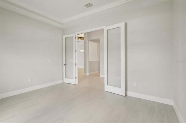 unfurnished room with light wood-style floors, baseboards, visible vents, and ornamental molding