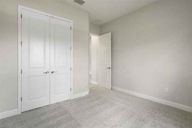 unfurnished bedroom featuring light carpet and a closet