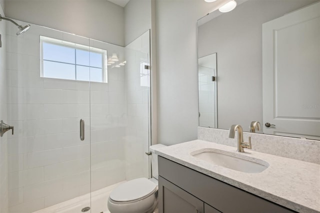 bathroom featuring a shower stall, toilet, and vanity