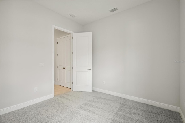 spare room with visible vents, baseboards, and light colored carpet