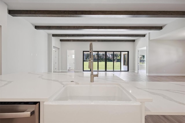 interior space with dishwasher, beamed ceiling, hardwood / wood-style floors, and sink