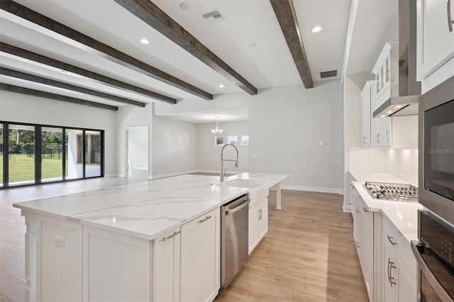 kitchen with white cabinets, appliances with stainless steel finishes, beamed ceiling, a large island, and light stone counters