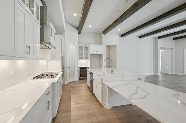 kitchen featuring white cabinets, beam ceiling, and light stone counters