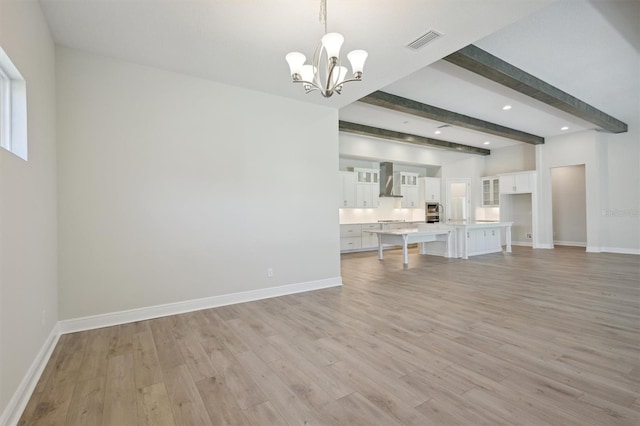 unfurnished living room featuring beamed ceiling, an inviting chandelier, and light hardwood / wood-style flooring