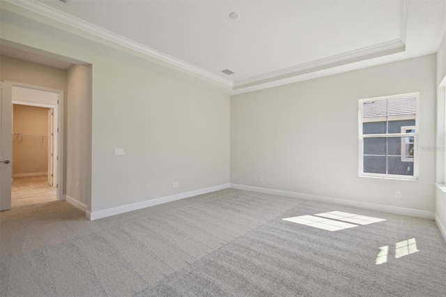 carpeted empty room with a raised ceiling and ornamental molding