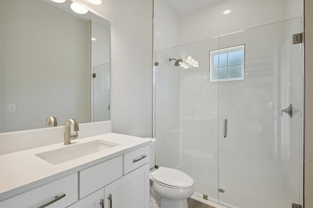 bathroom featuring vanity, a shower with shower door, and toilet