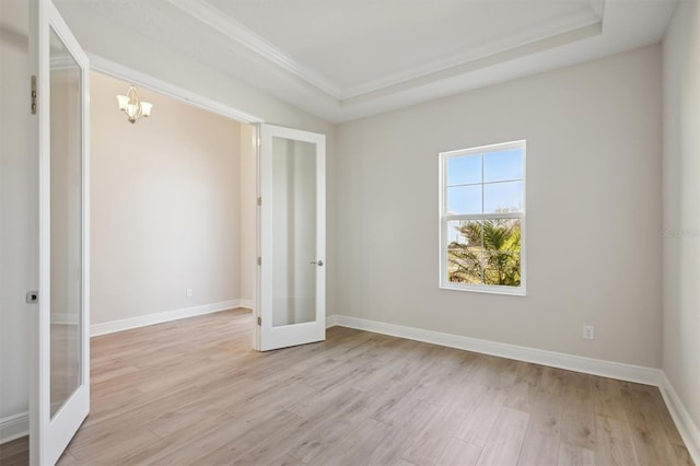 unfurnished bedroom with french doors, light wood-type flooring, and a tray ceiling