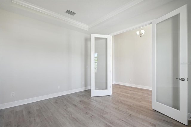 empty room featuring a chandelier, crown molding, french doors, and light hardwood / wood-style floors