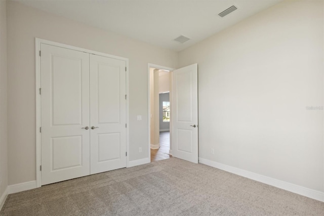 unfurnished bedroom featuring a closet and light colored carpet