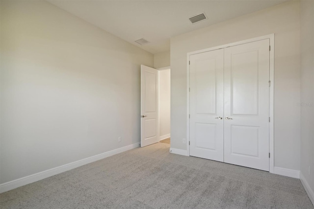 unfurnished bedroom featuring a closet and light colored carpet