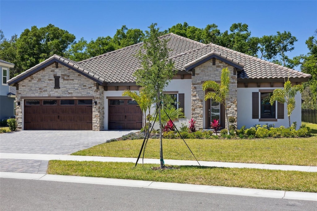 10183 Meadowrun Dr, Lithia, FL 33547 - ranch-style house with a tiled roof, a front yard, an attached garage, and stone siding