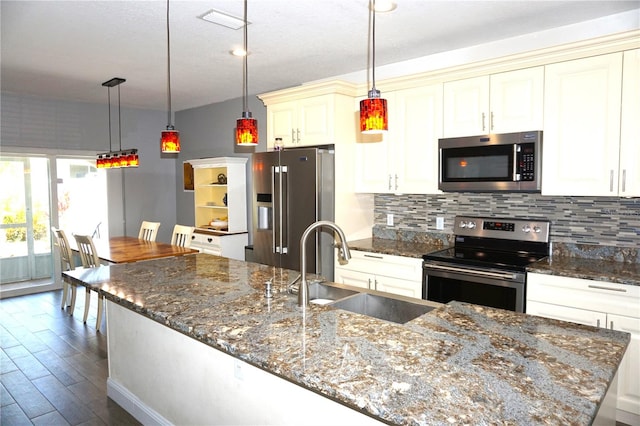 kitchen featuring hanging light fixtures, a center island with sink, tasteful backsplash, appliances with stainless steel finishes, and sink