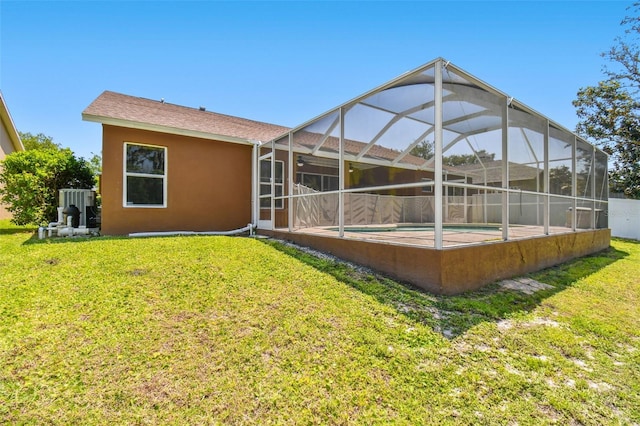 rear view of house featuring glass enclosure, a yard, and a fenced in pool