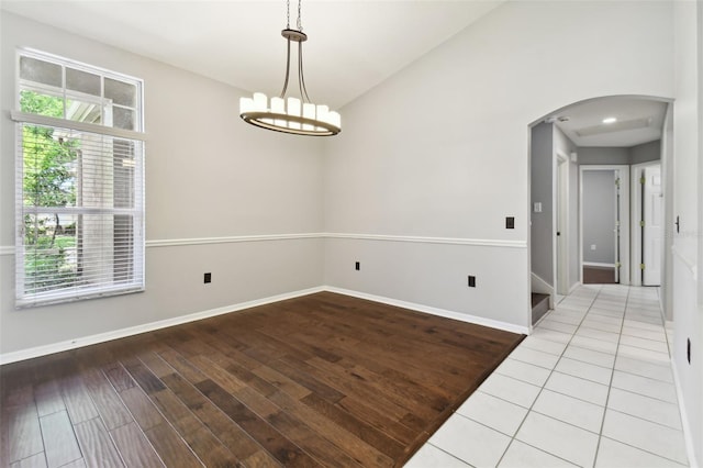 spare room with vaulted ceiling, tile floors, and a chandelier