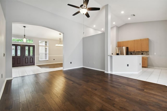 unfurnished living room with high vaulted ceiling, ceiling fan, and light tile floors