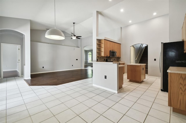 kitchen featuring appliances with stainless steel finishes, backsplash, light tile floors, and a kitchen island