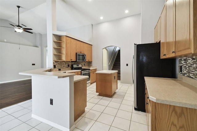 kitchen featuring tasteful backsplash, appliances with stainless steel finishes, high vaulted ceiling, and light tile flooring