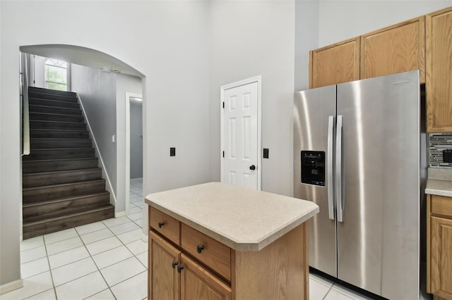 kitchen with stainless steel fridge with ice dispenser, light tile flooring, tasteful backsplash, and a kitchen island