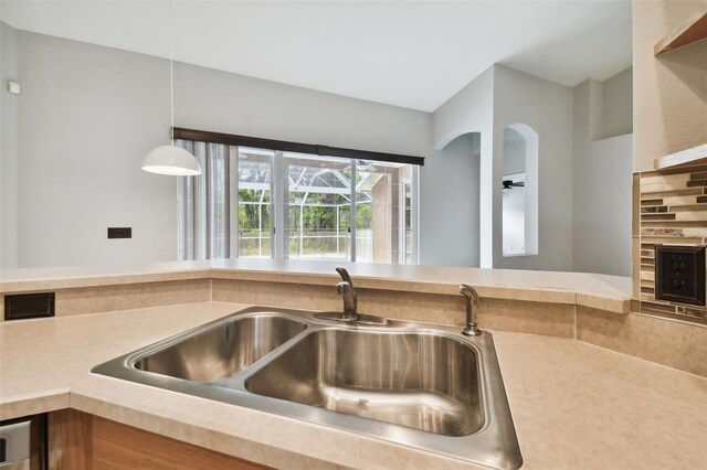 kitchen with hanging light fixtures, a fireplace, sink, and backsplash