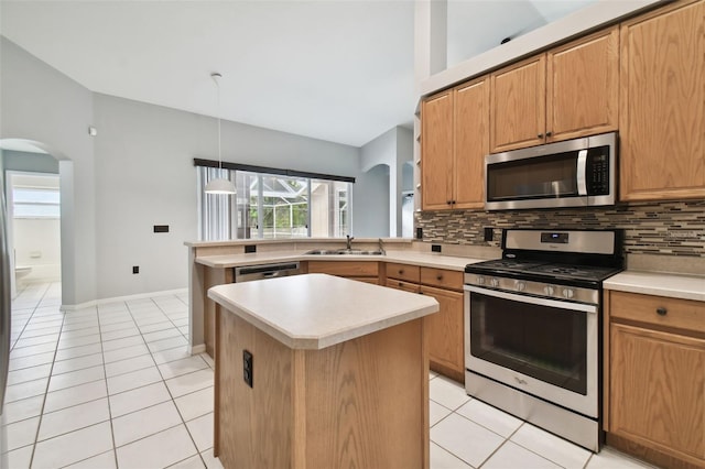 kitchen with decorative light fixtures, light tile flooring, backsplash, stainless steel appliances, and a kitchen island