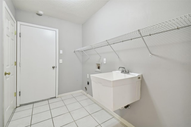 clothes washing area with light tile flooring, a textured ceiling, washer hookup, electric dryer hookup, and sink