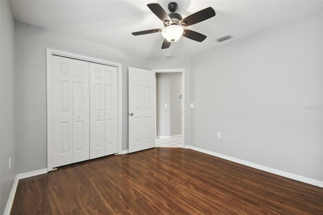 unfurnished bedroom with a closet, dark hardwood / wood-style flooring, and ceiling fan