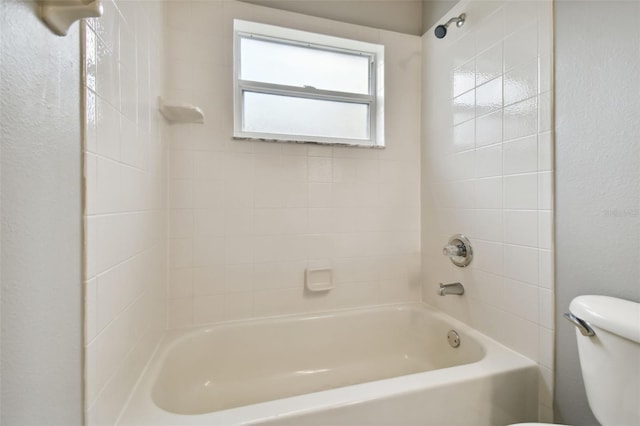 bathroom with tiled shower / bath combo and toilet